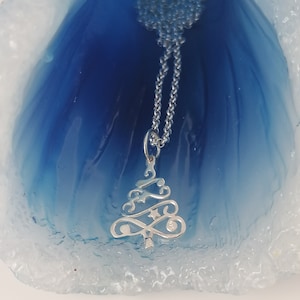 May include: A silver chain necklace with a delicate, ornate silver Christmas tree pendant. The pendant features a star and a small circle with the number 925.