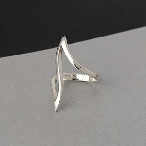 Peut inclure: Une bague en argent avec un design abstrait unique. La bague est faite d'une seule pièce de métal pliée en une forme pointue.
