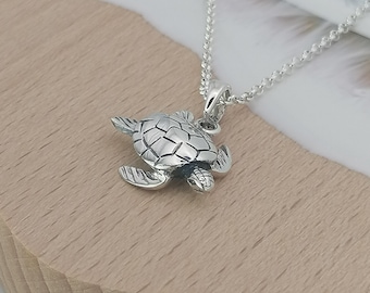 May include: A silver necklace with a detailed turtle pendant. The turtle is facing to the right and has a textured shell.