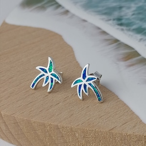 Puede incluir: Un par de pendientes de plata con forma de palmera con incrustaciones de ópalo azul y verde.