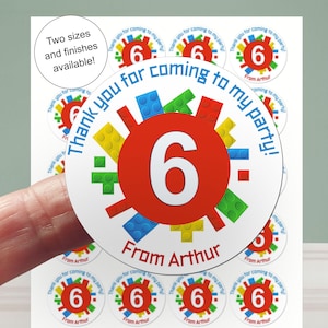 Op de afbeelding: Een vel stickers met een rode cirkel met het witte nummer 6. De stickers zeggen "Bedankt voor je komst naar mijn feest!" en "Van Arthur". Het ontwerp bevat kleurrijke blokvormen.