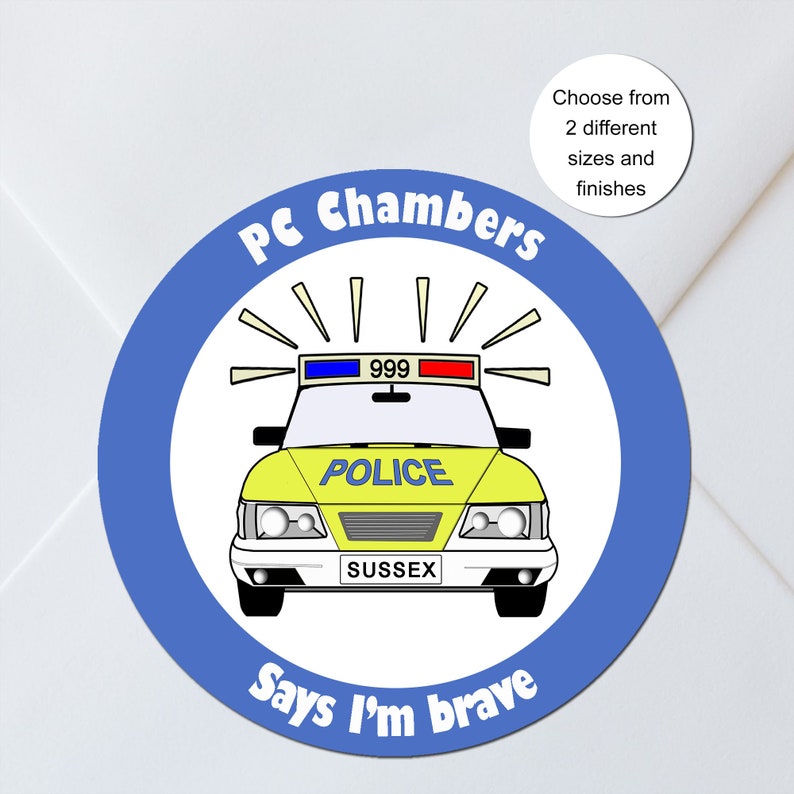 May include: A round sticker with a blue border and a cartoon police car in the center. The car is yellow and has the word "POLICE" on the hood. The text "PC Chambers" and "Says I'm brave" are in blue around the edge.