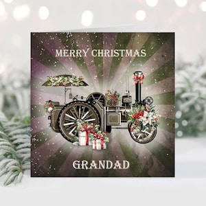 May include: A square Christmas greeting card featuring a vintage steam traction engine decorated with poinsettias, holly, and red bows. Two gift boxes sit in front of the wheels. The text reads MERRY CHRISTMAS at the top and GRANDAD at the bottom.