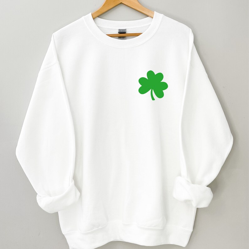 Puede incluir: Sudadera blanca con un gr&aacute;fico de tr&eacute;bol de cuatro hojas verde.