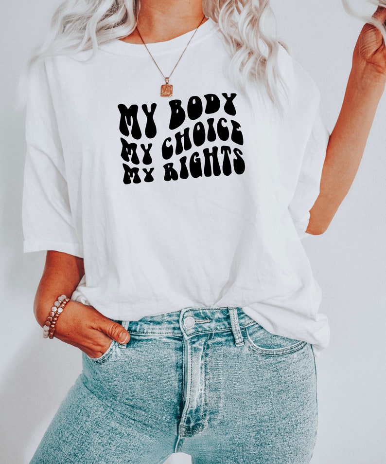 May include: White t-shirt with a black graphic that reads "My Body My Choice My Rights" in a retro font.