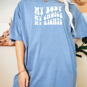 May include: A blue t-shirt with the text "MY BODY MY CHOICE MY RIGHTS" in white, stylized lettering.