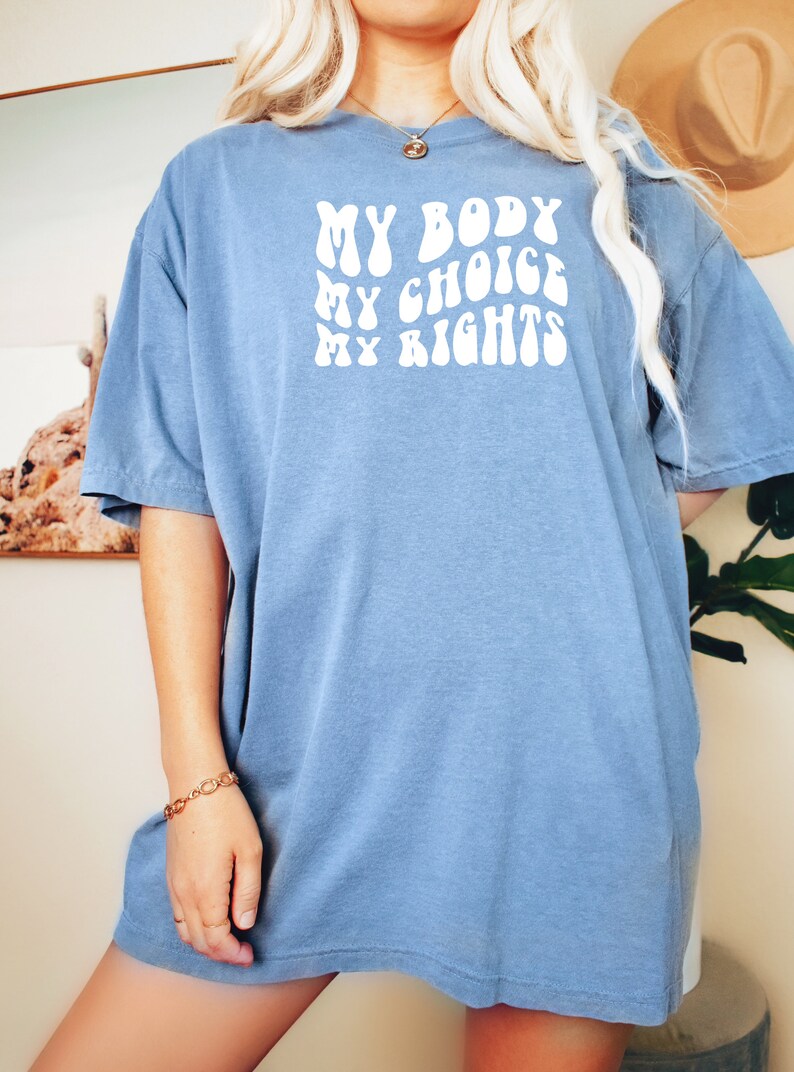 May include: A blue t-shirt with the text "MY BODY MY CHOICE MY RIGHTS" in white, stylized lettering.