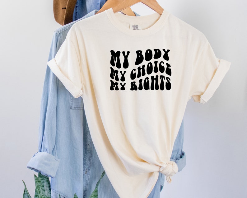 May include: A white t-shirt with black text that reads "MY BODY MY CHOICE MY RIGHTS" in a retro font.