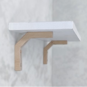Peut inclure: Étagère en bois blanche avec deux supports beiges. L'étagère rectangulaire est peinte en blanc. Les supports en forme de L sont en bois, conçus pour soutenir l'étagère. Design simple et moderne, adapté à divers intérieurs.