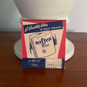 May include: A red, white, and blue calendar card for April 1942, advertising Softex Toilet Tissue. The card features a cartoon illustration of a roll of toilet paper with the text "A Quality Item To Build Volume!" and "Softex Toilet Tissue".