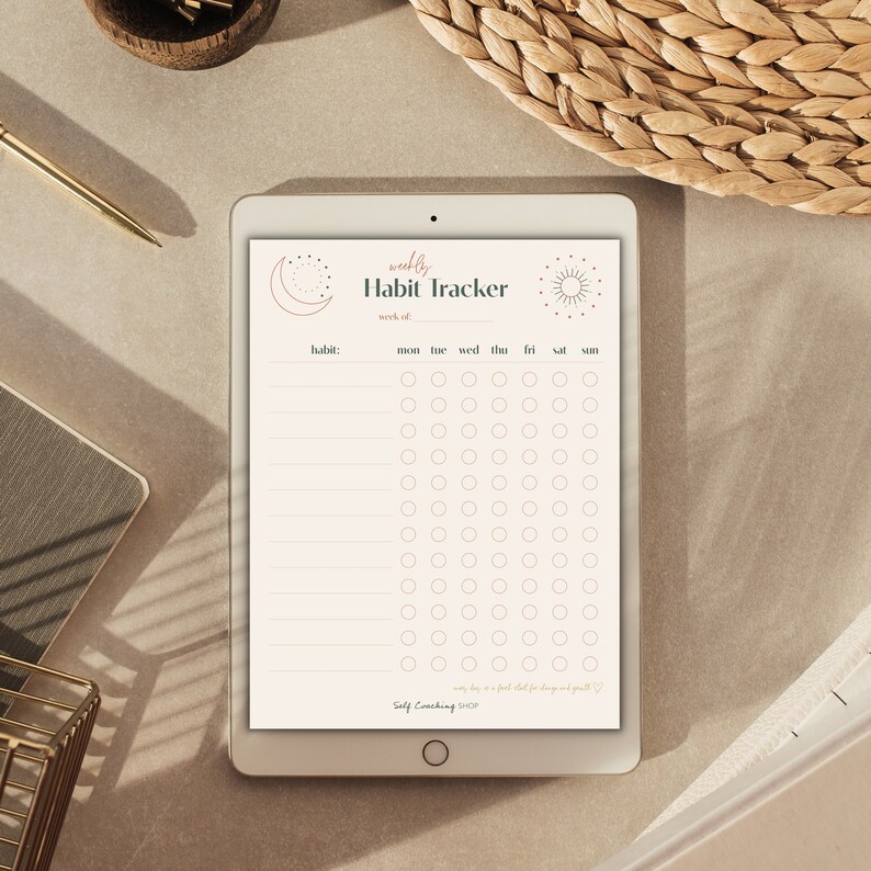 Puede incluir: Una tableta digital muestra un rastreador de h&aacute;bitos semanal beige. El rastreador incluye un encabezado con las palabras "weekly Habit Tracker" y una secci&oacute;n para rastrear h&aacute;bitos de lunes a domingo. Los dise&ntilde;os celestiales decorativos est&aacute;n en la parte superior.