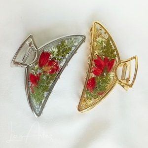 May include: Two triangular hair claw clips featuring clear resin frames filled with pressed red flowers and green foliage. One clip has a silver-toned metal hinge and frame, while the other features a gold-toned metal hinge and frame.