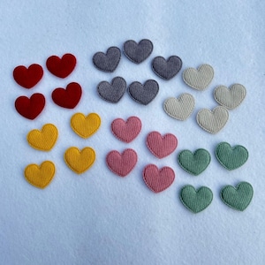 Könnte beinhalten: Sortiment an Filz-Herz-Patches in verschiedenen Farben, darunter Rot, Gelb, Rosa, Grau und Grün. Die Herzen sind alle gleich groß und gleich geformt und in einem zufälligen Muster angeordnet.
