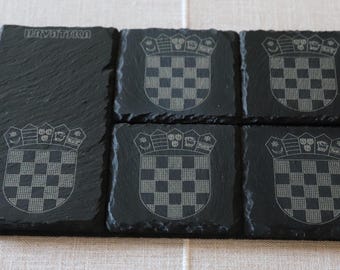 May include: Six black slate coasters with a white Croatian coat of arms design. The coasters are arranged in a rectangle with the word "Hrvatska" on the top left coaster.