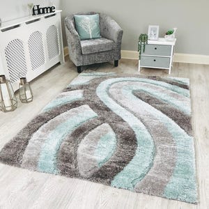 May include: A light blue and grey shag rug with a wavy abstract design. The rug is on a light wood floor.