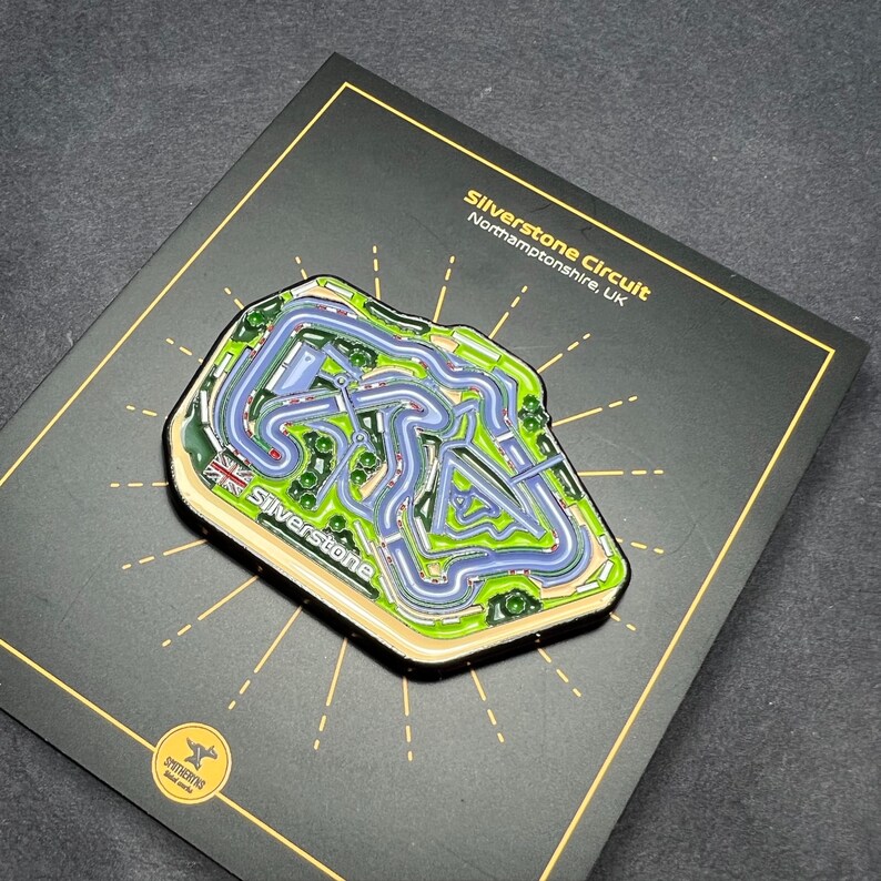 May include: A black enamel pin featuring a detailed map of the Silverstone Circuit in Northamptonshire, UK. The pin is surrounded by a gold starburst design and the text "Silverstone Circuit" and "Northamptonshire, UK".