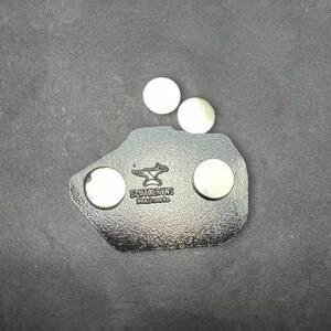 May include: Black leather patch with four silver metal snaps and a small anvil logo with the text "SOMETHING SPECIAL" underneath.