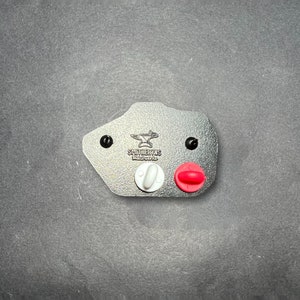 May include: A gray leather patch with a black anvil and the text "SHULTERUS Metalcraft, Inc." in white. The patch has two black rivets and two small pins, one white and one red.
