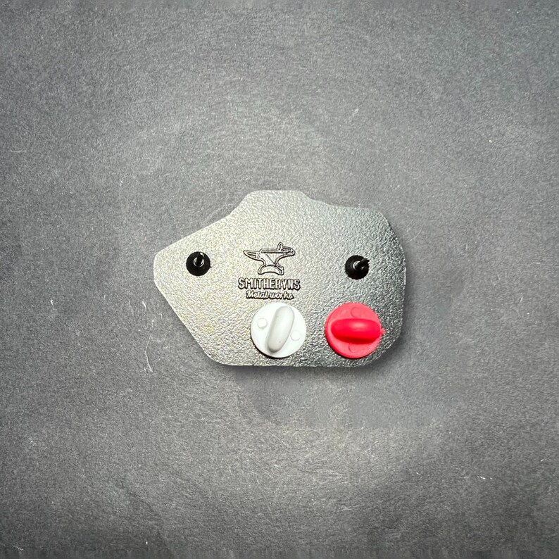 May include: A gray leather patch with a black anvil and the text "SHULTERUS Metalcraft, Inc." in white. The patch has two black rivets and two small pins, one white and one red.