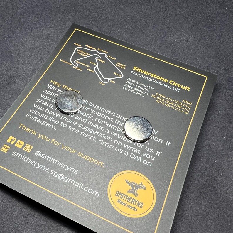May include: A black and white image of the Silverstone Circuit race track in Northamptonshire, UK. The image includes the track layout, the name of the circuit, and the location. The text also includes the date of the first Grand Prix, the track length, the race distance, and the coordinates of the circuit. The image also includes two silver metal magnets.