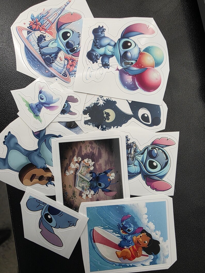 May include: A collection of colorful stickers featuring the character Stitch from the animated film Lilo & Stitch. The stickers depict Stitch in various poses, including holding balloons, surfing, and on a planet. The stickers are on a black surface.