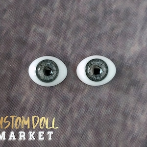 May include: Two doll eyes with a gray iris and a white sclera. The irises have a detailed, textured pattern. The text "CUSTOM DOLL MARKET" is printed in gold and white at the bottom of the image.