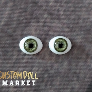 May include: Two doll eyes with a green iris and a white sclera. The irises have a detailed, textured pattern. The text "CUSTOM DOLL MARKET" is visible in gold and white.