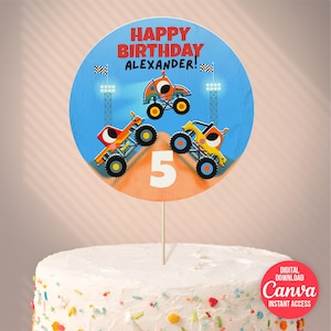 May include: A round cake topper with the text "HAPPY BIRTHDAY ALEXANDER!" and three cartoon monster trucks. The number "5" is in the center. The topper is on a white frosted cake with colorful sprinkles.
