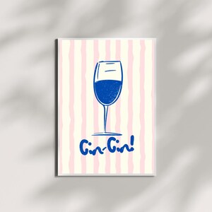 May include: A framed print featuring a blue wine glass illustration with the phrase "Gin-Gin!" in a playful font. The background has vertical stripes in pink and off-white, creating a cheerful and inviting aesthetic.