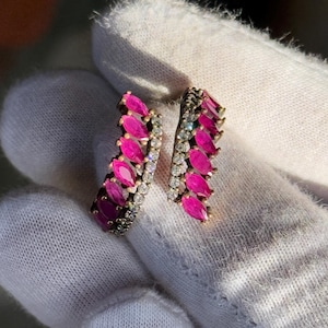 Op de afbeelding: Een paar zilveren oorbellen met een dubbele rij roze marquisevormige stenen, gezet in een pavé-setting.