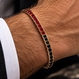 Puede incluir: Una pulsera de tenis dorada con una hilera de piedras preciosas de corte cuadrado. La pulsera está dividida en dos secciones, con una mitad engastada con piedras rojas vibrantes y la otra mitad con piedras negras profundas en un marco de oro.