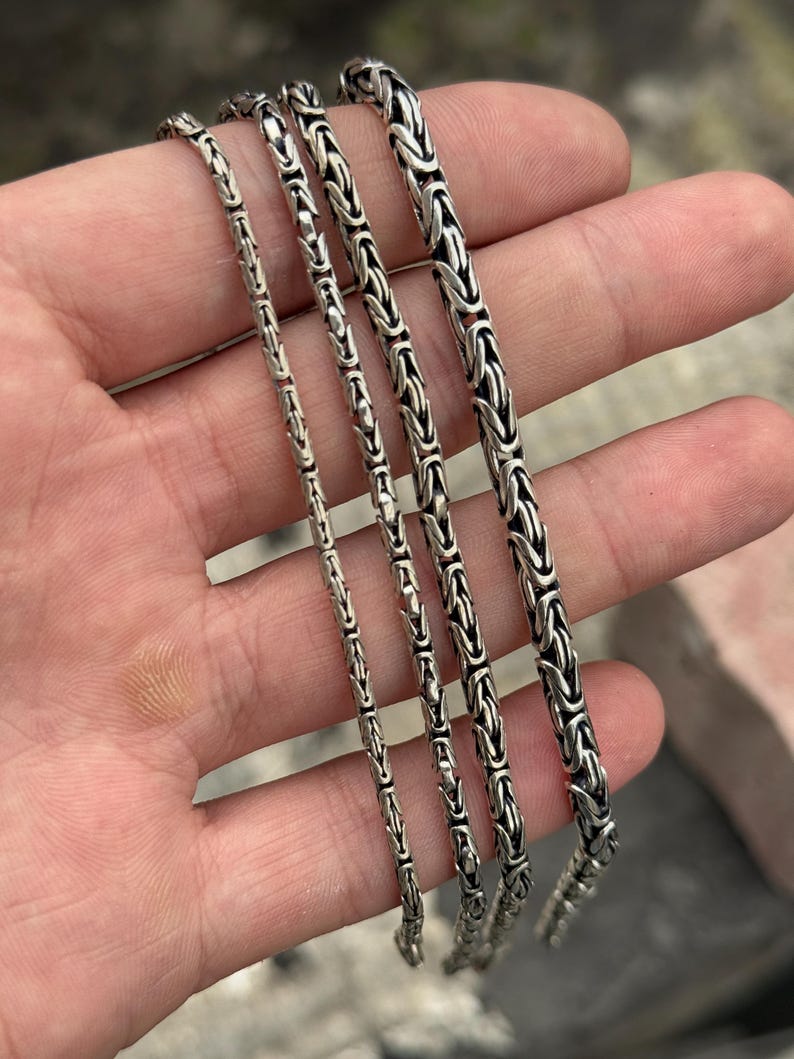May include: Four silver chain necklaces of varying lengths and widths. The chains are all made of a tightly woven, box-style design.