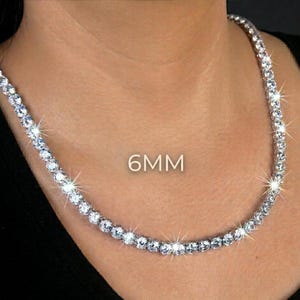 May include: A sparkling necklace with numerous round, clear gemstones. The necklace is 6mm in size and is worn around the neck. The gemstones are set closely together, creating a continuous line of brilliance. The necklace is displayed against a dark background.