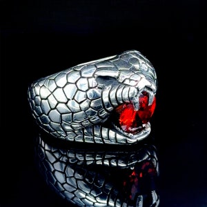 Peut inclure: Une bague en argent en forme de tête de serpent avec une pierre précieuse rouge pour l'œil.