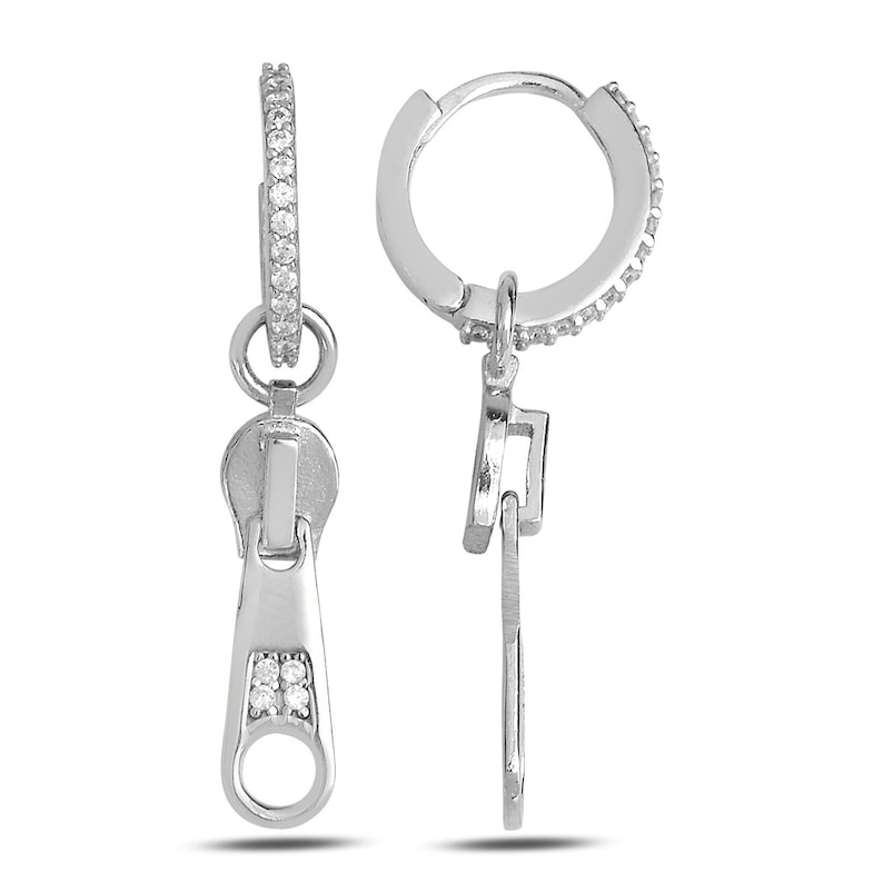 May include: Silver hoop earrings with a zipper charm. The zipper charm has a small row of clear cubic zirconia stones.