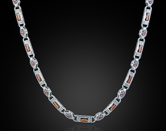 May include: Silver-toned necklace with rectangular amber-colored stones and small red accents. The chain links are detailed with floral and geometric patterns. The necklace is displayed against a dark background, highlighting its intricate design.