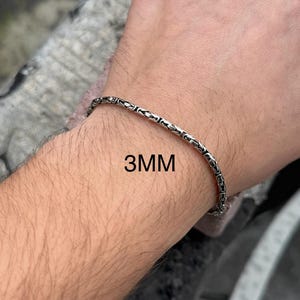 May include: A silver chain bracelet with a box chain design. The bracelet is 3mm wide.