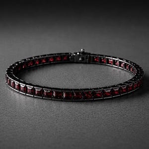 Könnte beinhalten: Ein silbernes Armband mit dunklem Finish, besetzt mit zahlreichen quadratisch geschliffenen, tiefroten Edelsteinen. Das Armband wird auf einer grauen Oberfläche präsentiert, wobei die Edelsteine das Licht reflektieren.