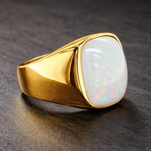 May include: A gold signet ring featuring a smooth, polished band and a large, rectangular, cabochon-cut white opal gemstone. The opal displays iridescent flashes of color across its surface, set securely within the solid gold metal frame.