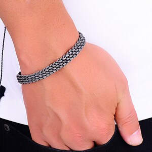 May include: A silver braided bracelet with a woven design.