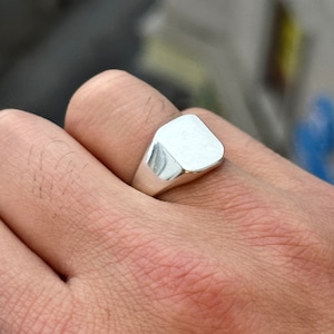 May include: A silver signet ring with a square face.