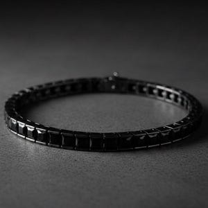 Puede incluir: Un brazalete negro con piedras cuadradas. El brazalete es de metal oscuro y tiene un cierre de broche. Las piedras están espaciadas uniformemente, creando una banda continua.