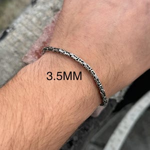 May include: A silver chain bracelet with a 3.5 mm width. The bracelet is shown on a person's wrist.