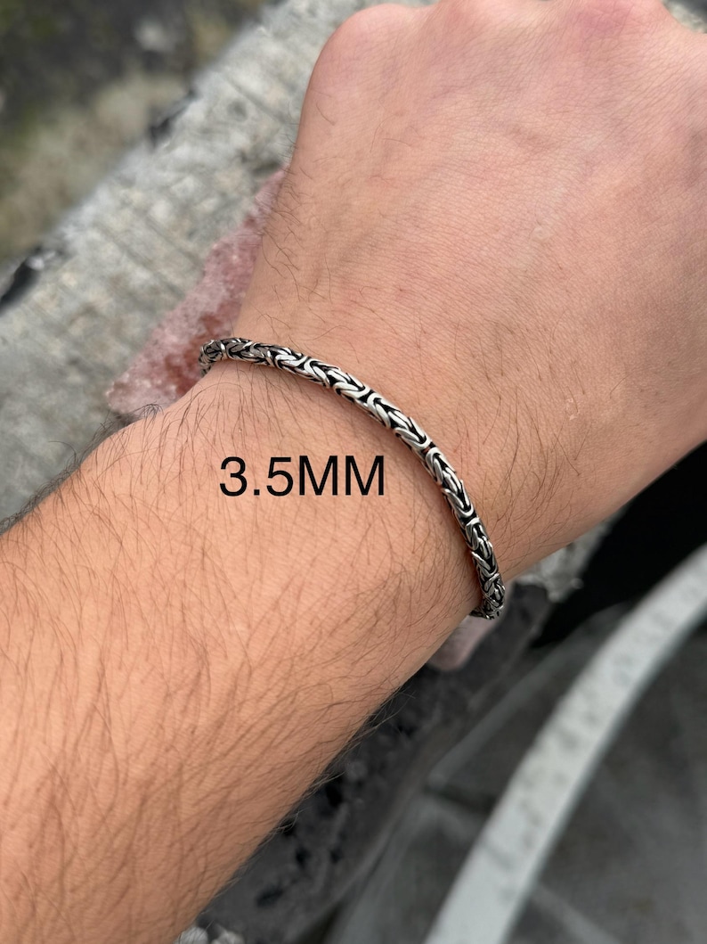 May include: A silver chain bracelet with a 3.5 mm width. The bracelet is shown on a person's wrist.