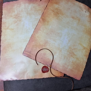 May include: Two blank parchment scrolls with a brown leather cord and a red wax seal with a crown design.