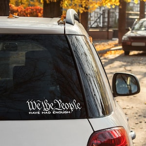 May include: A white car with a sticker on the back window that says "We the People Have Had Enough".