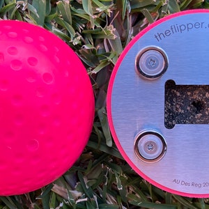 K&ouml;nnte beinhalten: Ein rosa Gummiball mit einer strukturierten Oberfl&auml;che und einem silbernen Metallsockel mit vier Magneten. Der Sockel tr&auml;gt den Text "theflipper.com.au" und "AU Des Reg 202014958".