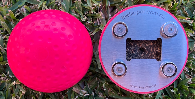 K&ouml;nnte beinhalten: Ein rosa Gummiball mit einer strukturierten Oberfl&auml;che und einem silbernen Metallsockel mit vier Magneten. Der Sockel tr&auml;gt den Text "theflipper.com.au" und "AU Des Reg 202014958".