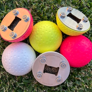 K&ouml;nnte beinhalten: F&uuml;nf runde B&auml;lle in verschiedenen Farben mit einer strukturierten Oberfl&auml;che. Jeder Ball hat eine magnetische Basis mit einem Flaschen&ouml;ffner. Die Basen sind aus Metall und Holz. Der Text "theflipper.com.au" ist auf den Basen aufgedruckt.
