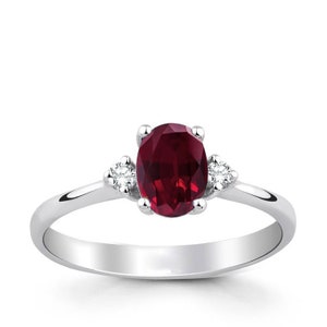 May include: A silver ring with a large oval-shaped ruby gemstone and two smaller diamond accents.